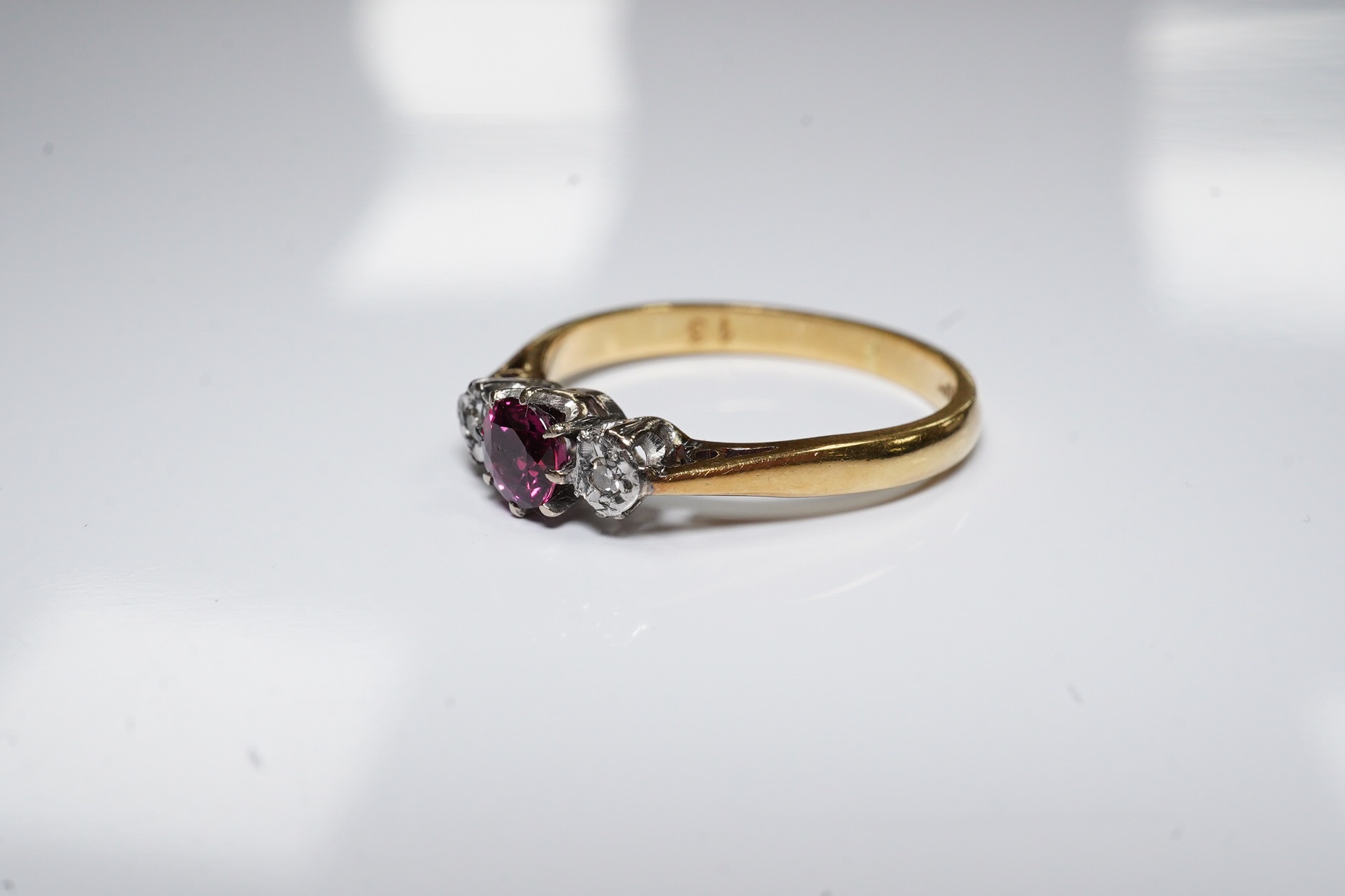 An 18ct and platinum ruby and diamond set three stone ring, size O, gross weight 3.1 grams. Condition - fair